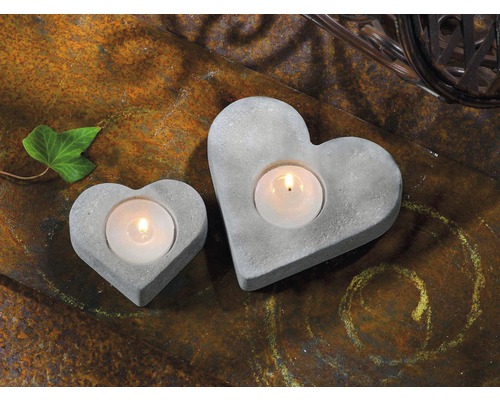 Zwei herzförmige Teelichthalter aus Beton auf rustikalem Untergrund