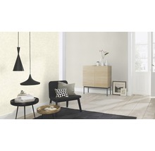 Salon avec papier peint à motifs, fauteuil noir, tapis noir et suspension.