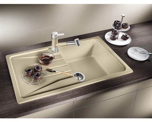 Beige Küchenspüle mit Abtropffläche, Armatur und einigen Backwaren