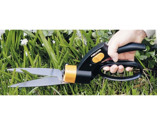 Eine Person schneidet Gras mit einer Grasschere von Fiskars.