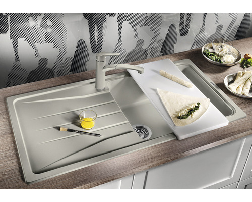 Évier de cuisine avec planche à découper, robinet, plats et ustensiles de cuisine sur un plan de travail