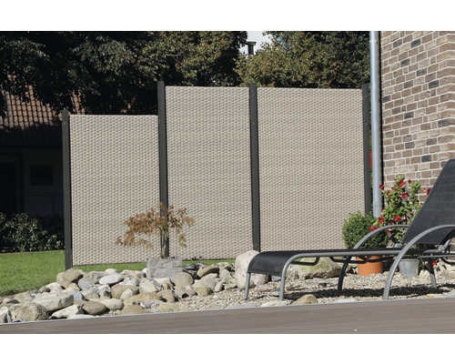 Scène de jardin avec écran d''intimité en rotin, pierres et chaise longue sur une terrasse