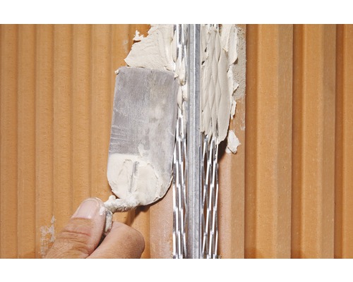 Une personne applique du mortier sur un angle de mur avec une spatule