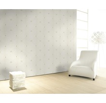 Pièce lumineuse avec papier peint à motifs, fauteuil et lampadaire.