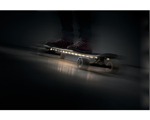 Person auf einem Skateboard mit LED-Beleuchtung in Bewegung.