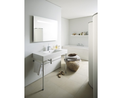 Salle de bain lumineuse avec lavabo sur pieds, miroir, baignoire et décoration