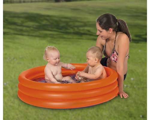 Aufblasbares Planschbecken mit zwei Kindern und einer Frau im Garten.
