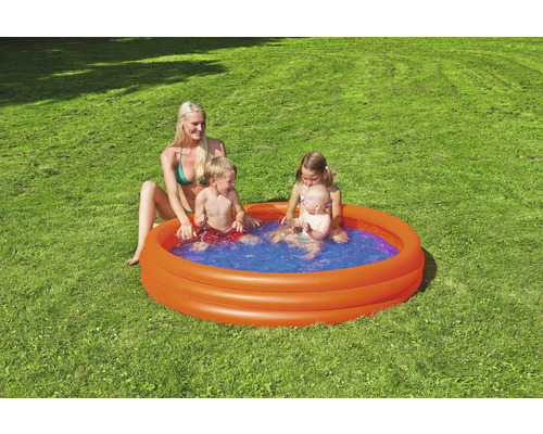 Aufblasbares Planschbecken mit spielenden Kindern und einer Frau im Garten.