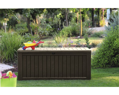 Gartenszene mit einer grossen, dunklen Gartenbox unter einem Spielzeugwagen.