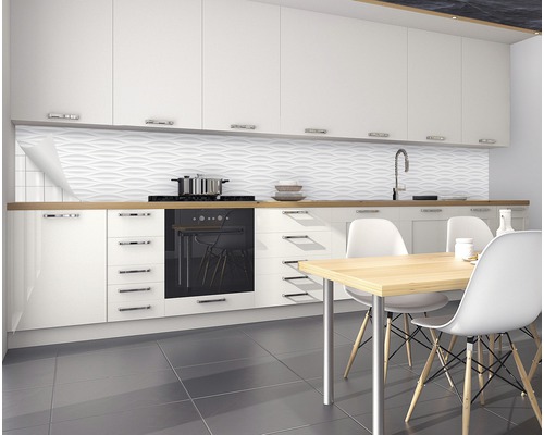 Cuisine moderne avec armoires blanches, évier, plaque de cuisson, table à manger et revêtement mural structuré.