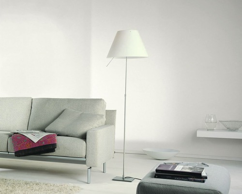 Salon avec canapé, lampadaire et pile de livres