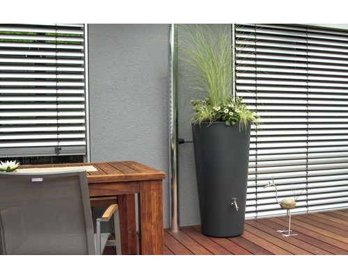 Scène avec réservoir d''eau de pluie, planté de fleurs et d''herbes, à côté d''une gouttière, sur une terrasse avec plancher en bois