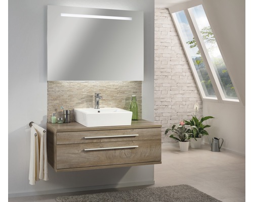 Badezimmer mit Waschtisch, Spiegel mit Beleuchtung, Handtuch und Pflanzen