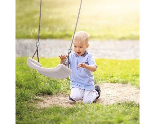 Bambin agenouillé sur une pelouse jouant avec une balançoire.