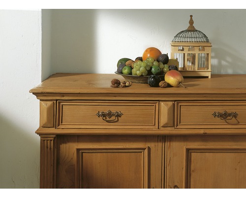 Commode en bois avec tiroirs, sur laquelle reposent une coupe de fruits et une cage à oiseaux