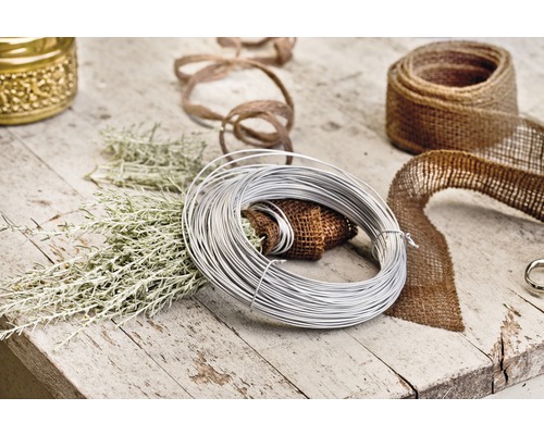 Dekorationsmaterialien wie Draht, Juteband und Pflanzenzweige auf einem Holztisch