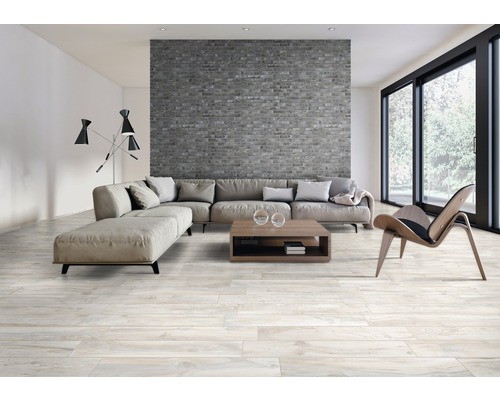 Salon avec mur en briques grises, canapé, table basse et parquet en bois clair