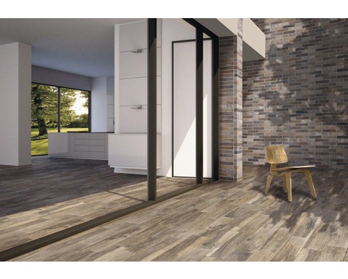 Pièce lumineuse avec parquet, mur en briques et chaise.