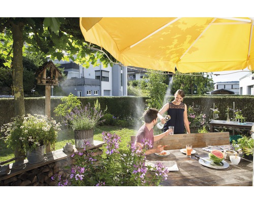 Szene im Garten mit Tisch, Sonnenschirm und kühlendem Nebelsystem