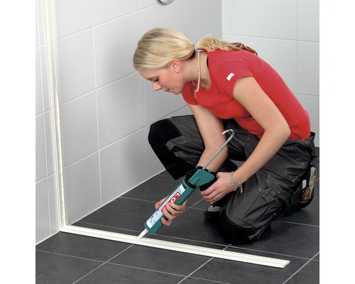 Frau dichtet Dusche mit Dichtstoff und Kartuschenpistole im Badezimmer ab