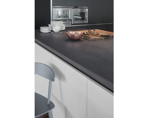 Moderne Küche mit dunkler Arbeitsplatte, Geschirr, Schüssel und Brot auf einem Schneidebrett.