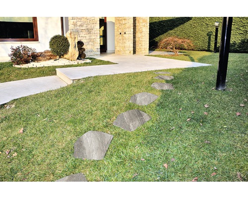 Außenaufnahme eines Gartens mit Rasen und Steinplatten als Gehweg zum Haus.