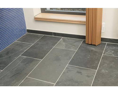 Salle de bains avec carrelage au sol et faïence murale bleue.