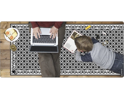 Dekorativer Teppich mit geometrischem Muster, genutzt von Erwachsenem mit Laptop und Kind mit Buch