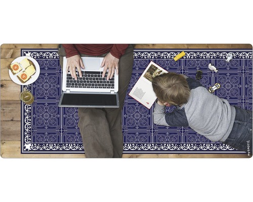 Person mit Laptop und Kind auf einer Spielmatte mit Muster