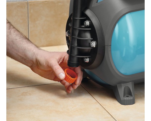 Eine Person schraubt eine orangefarbene Kappe auf eine Gartenpumpe.