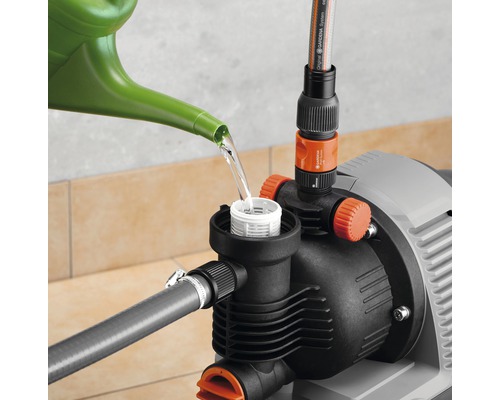 Gartenpumpe wird mit einer Gießkanne befüllt