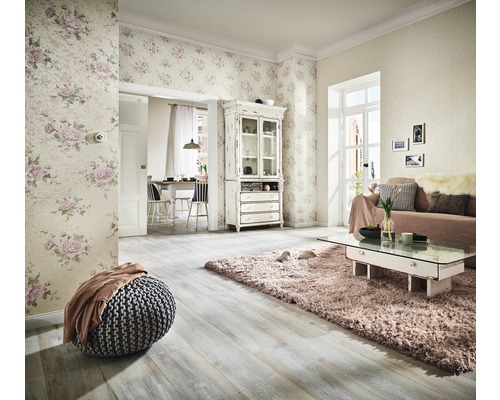 Salon avec papier peint floral, canapé, tapis et parquet pour une ambiance lumineuse.