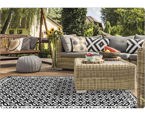 Terrassenszene mit Gartenmöbeln und einem schwarz-weissen geometrischen Teppich