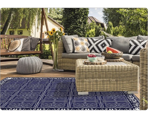 Terrasse mit Rattanmöbeln, Schaukelbank und blau gemusterter Outdoor-Teppich