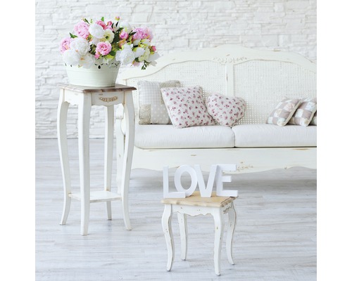 Dekoratives Interieur mit Blumenarrangement, Beistelltischen, Kissen und Sofa.