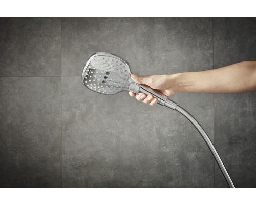 Main tenant une pomme de douche avec flexible.