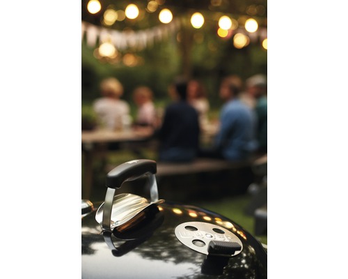 Weber Grill im Garten mit einer Gruppe von Personen im Hintergrund