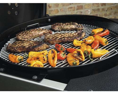 Grill mit Steaks und Paprika auf dem Rost.