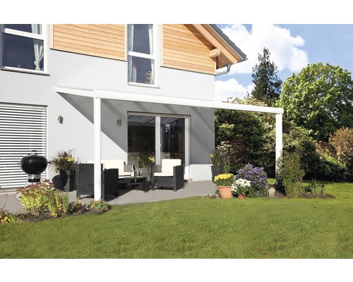 Terrasse avec toit de terrasse, meubles de jardin et barbecue sur une pelouse devant une maison