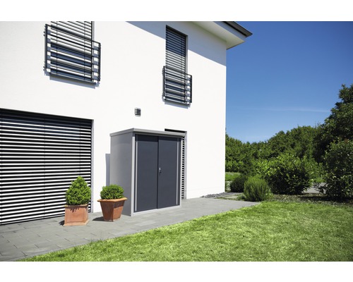 Abri de jardin métallique avec porte coulissante à côté d''une maison moderne avec des stores