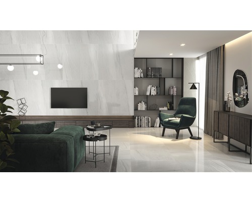 Salon lumineux avec carrelage au sol, canapé, fauteuil et étagères.