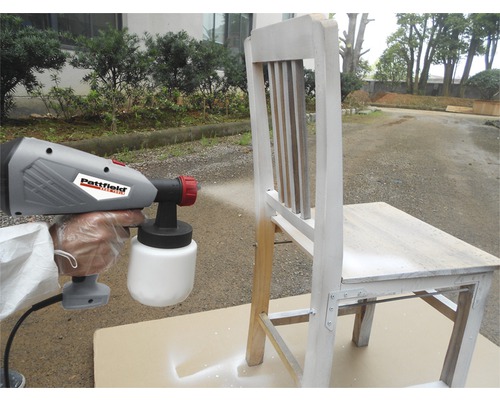 Système de pulvérisation de peinture peignant une chaise en bois