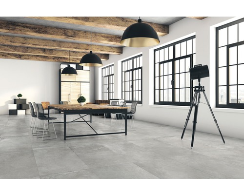 Heller Raum mit Betoneffekt Fliesen, Holzbalken und Büromöbeln.