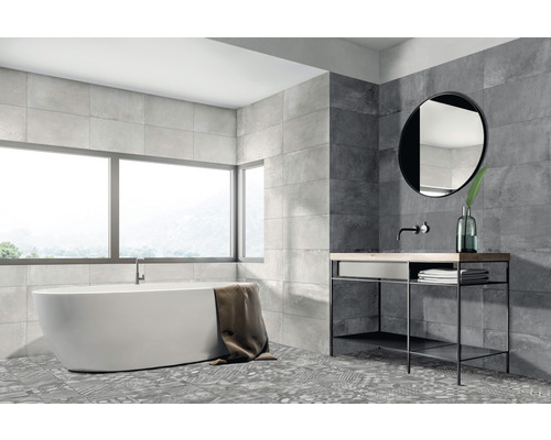 Helles Badezimmer mit Badewanne, Waschtisch, Spiegel und grauen Wand- und Bodenfliesen