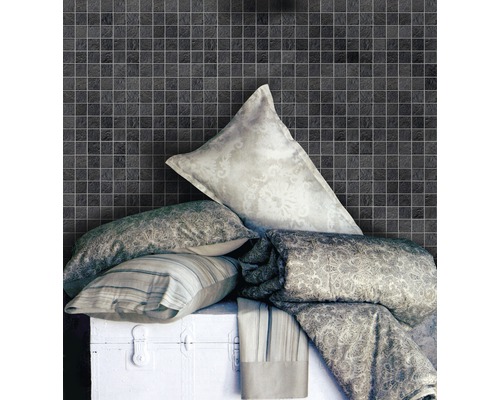 Scène avec des carreaux de mosaïque au mur, des coussins et des couvertures sur un coffre blanc.