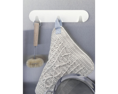 Scène de cuisine avec une brosse à vaisselle, un gant de cuisine et une passoire sur une barre de suspension