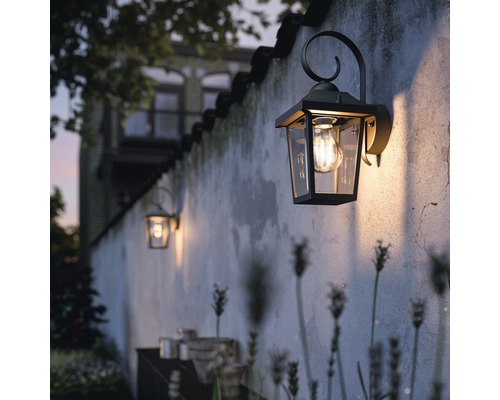 Aussenwandleuchten an einer Wand beleuchten einen Gartenbereich.