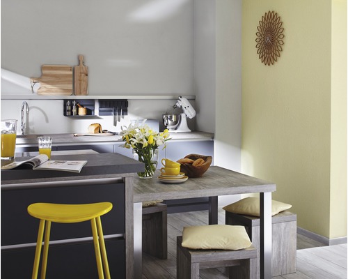 Cuisine lumineuse avec table à manger, tabourets, vaisselle et appareils de cuisine.