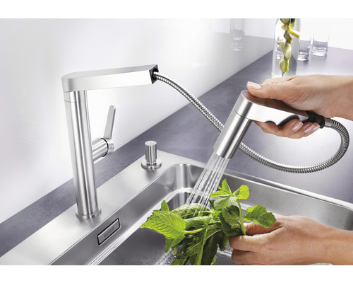 Robinet de cuisine avec douchette et personne lavant des herbes