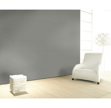 Heller Raum mit grauer Struktur-Tapete, Sessel und Papierstapel